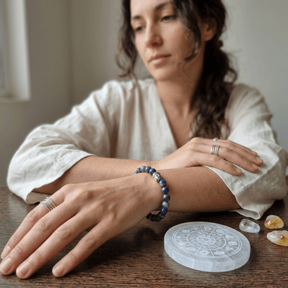 Woman wearing lapis lazuli natural stone bracelet, surrounded by crystals, promoting serenity and wisdom.