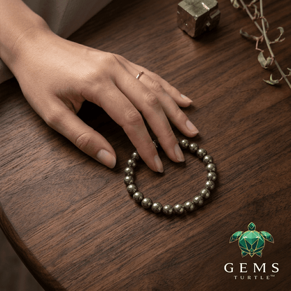 Raw Pyrite Wealth Bracelet showcasing authentic pyrite beads on a wooden table with a hand gently touching it.